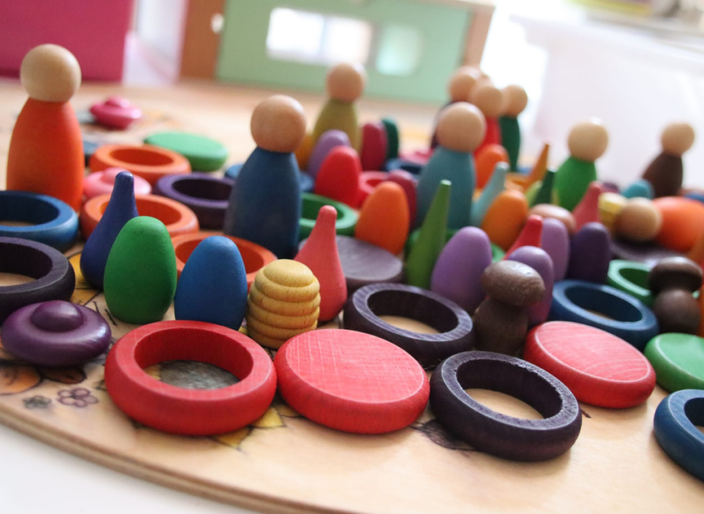 Houten poppetjes, ringen en schijven in vrolijke kleuren op een speeltafel